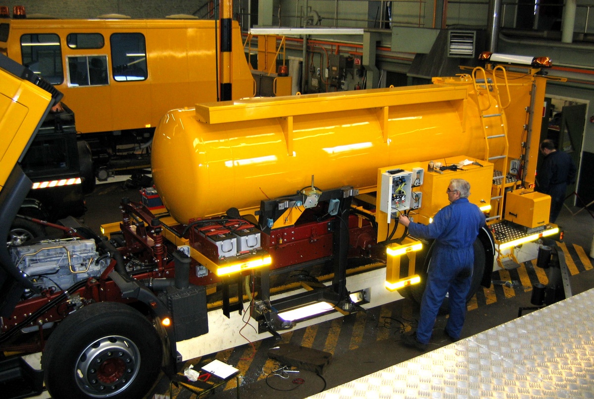 Engineer running tests on a yellow WDM highway survey vehicle in a warehouse